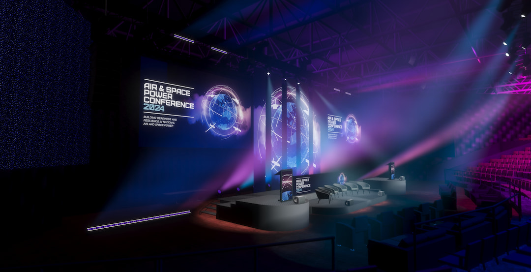 A large, dark conference hall with stage lighting and glowing blue and purple effects. Multiple screens display Air & Space Power Conference 2024. Rows of seating face a modern stage with podiums and LED screens.