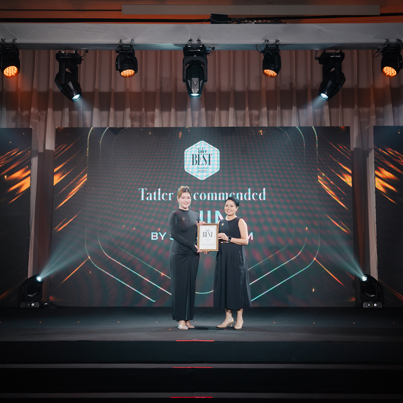 Two women in black outfits stand on a stage, smiling and holding an award plaque. A large screen behind them displays Tatler Recommended Best with stage lights shining above—an impressive showcase by a leading event production Thailand team.
