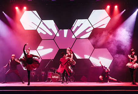 A group of dancers performs energetically on stage with dramatic lighting, geometric LED screens, and smoke effects, building a dynamic and artistic atmosphere that leaves the crowd eagerly anticipating an encore.