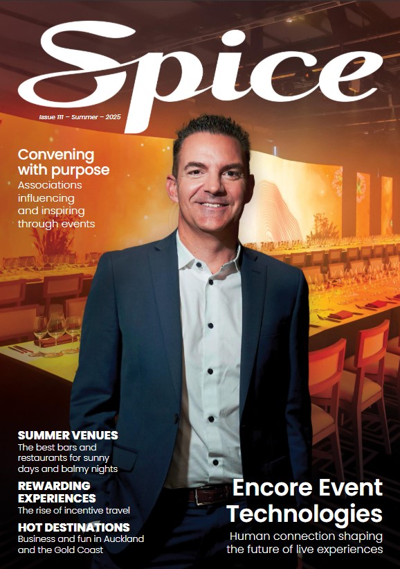 A man in a suit stands smiling in front of a modern, warmly lit event space. The cover text reads “Spice,” with articles on event technologies, destinations, summer venues, and fostering human connection in a digital world.