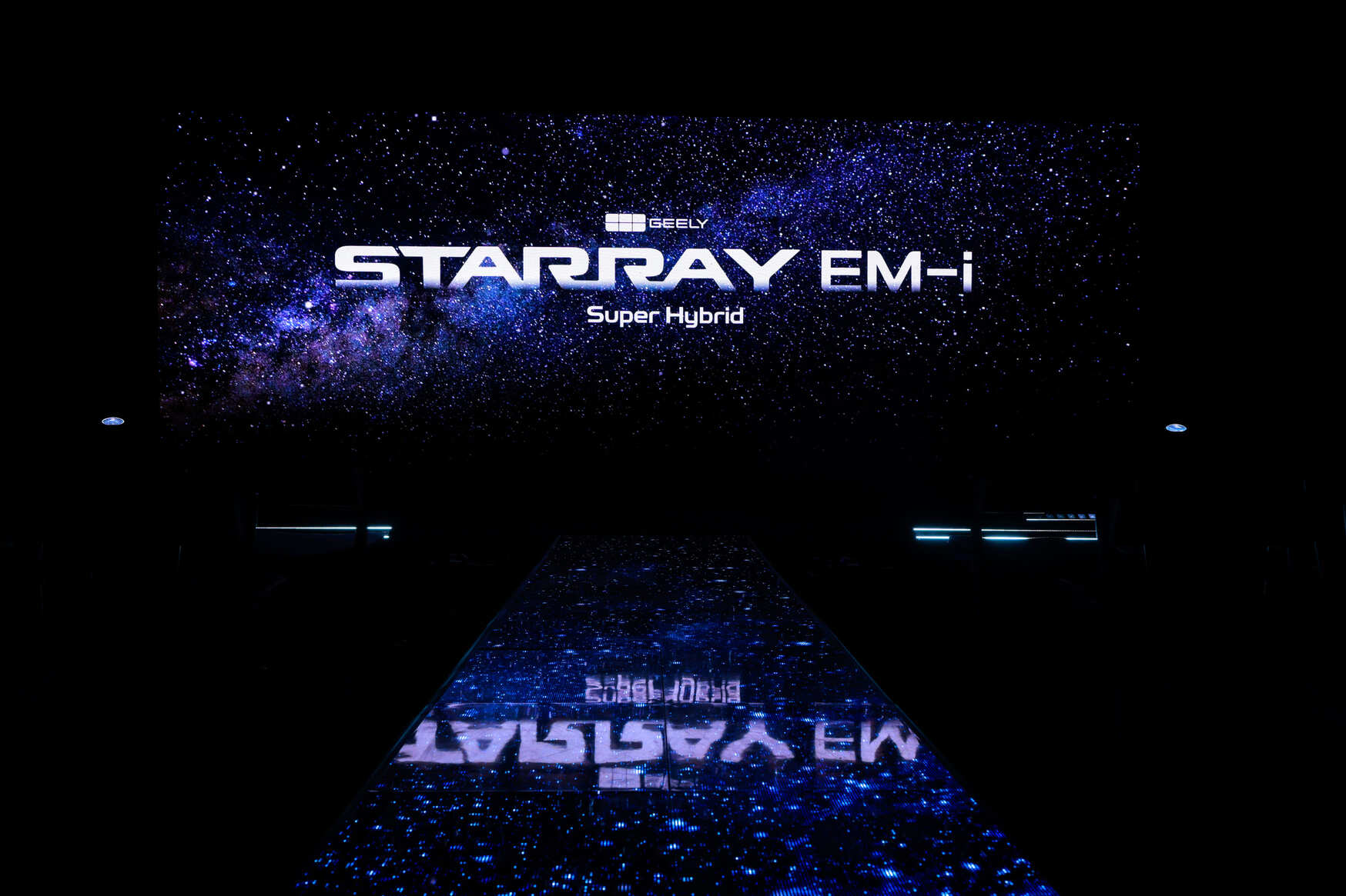 A dark stage with a starry background displays the words GEELY STARRAY EM-i Super Hybrid in large, bright letters, with reflections on a glossy floor.