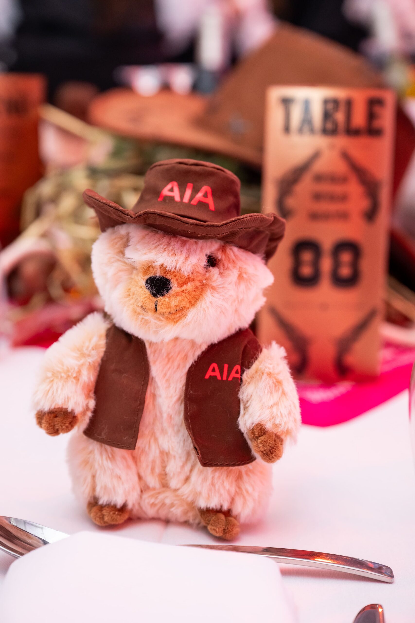 Branded AIA teddy bear styled with a cowboy hat displayed on an event table - Encore Event Technologies