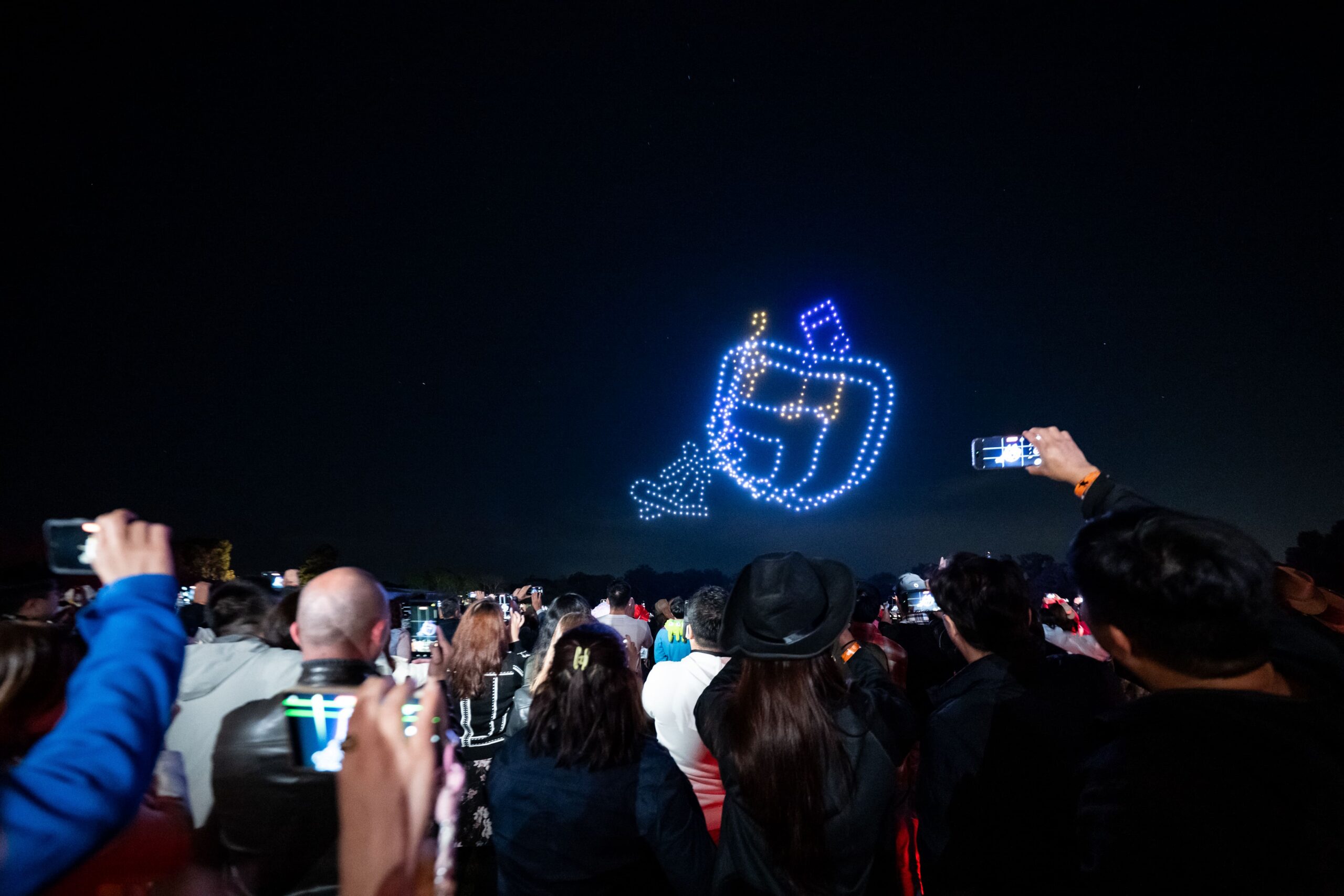 Drone light show forming AIA symbol in night sky above event crowd - Encore Event Technologies