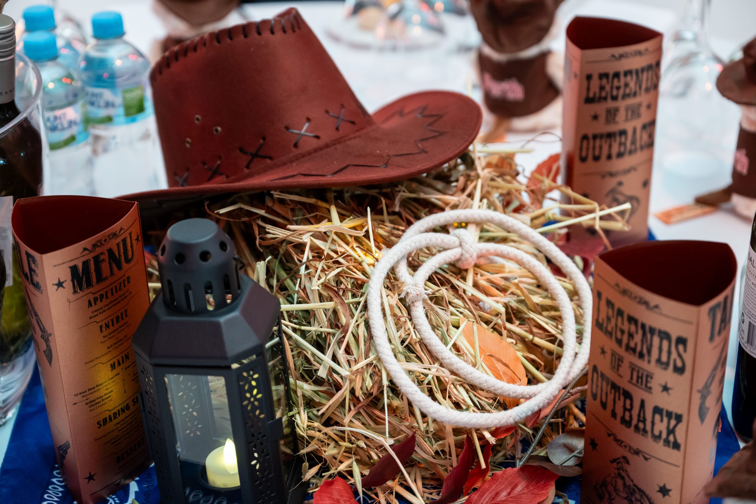 Western themed table centrepiece with hay bale, rope, lantern and cowboy hat at an AIA event - Encore Event Technologies