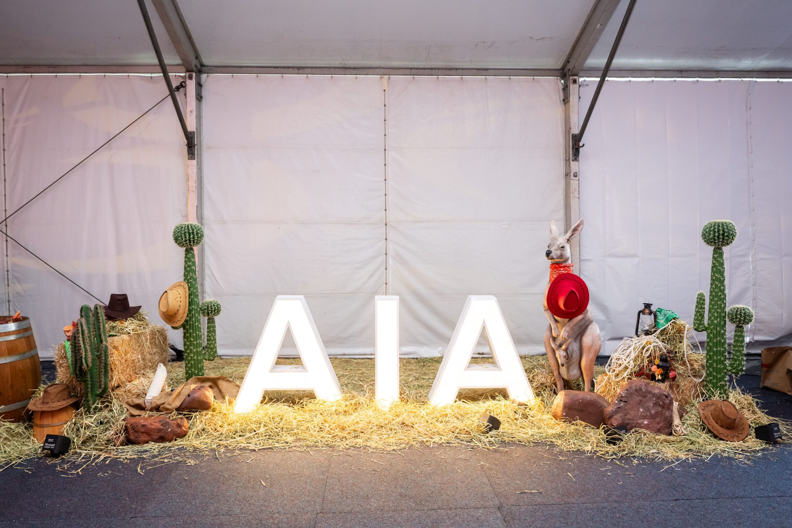 Illuminated AIA letters staged with western props and hay bales inside an event marquee - Encore Event Technologies