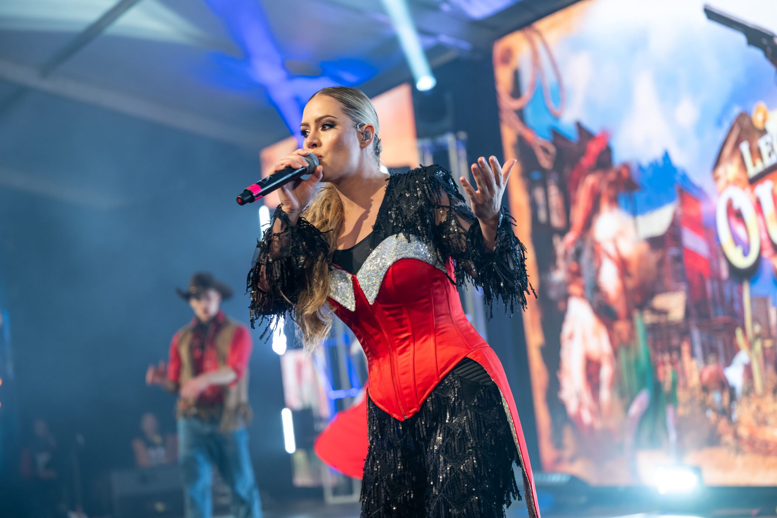 Lead vocalist performing on stage in western themed costume with live band behind - Encore Event Technologies