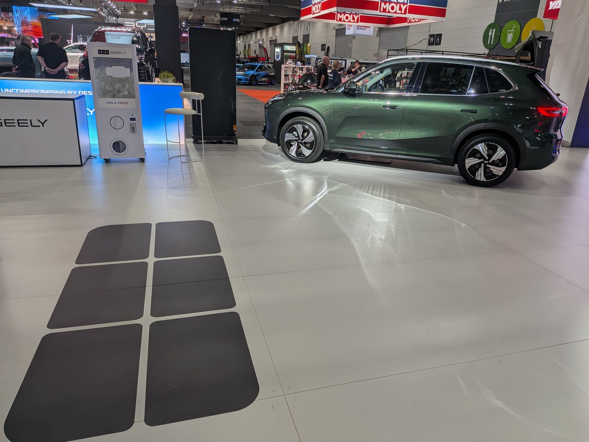 Green Geely SUV displayed on exhibition floor beside floor decals and booth setup - Encore Event Technologies