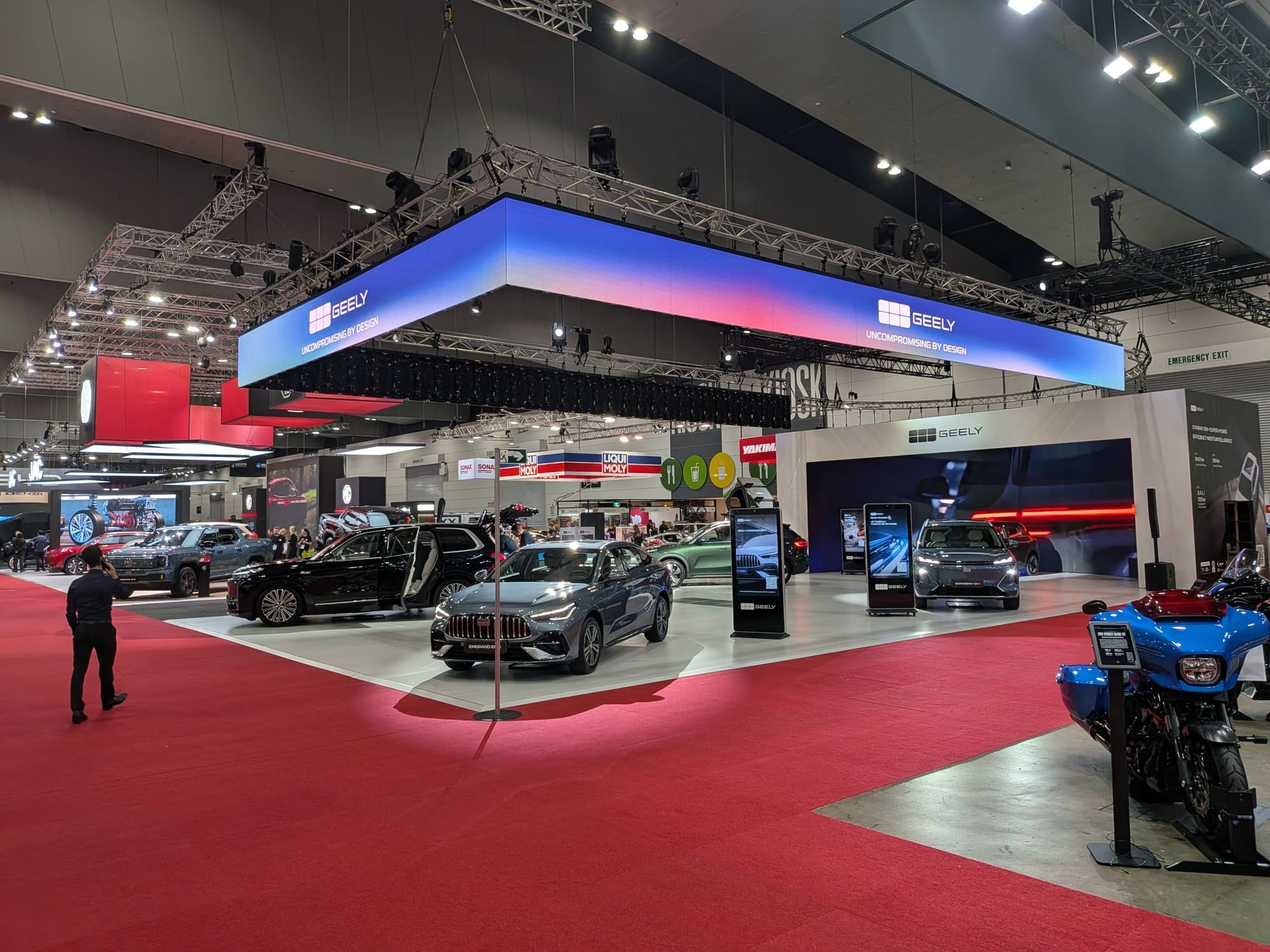 Wide shot of Geely exhibition area with overhead lighting rig and multiple vehicles on display - Encore Event Technologies
