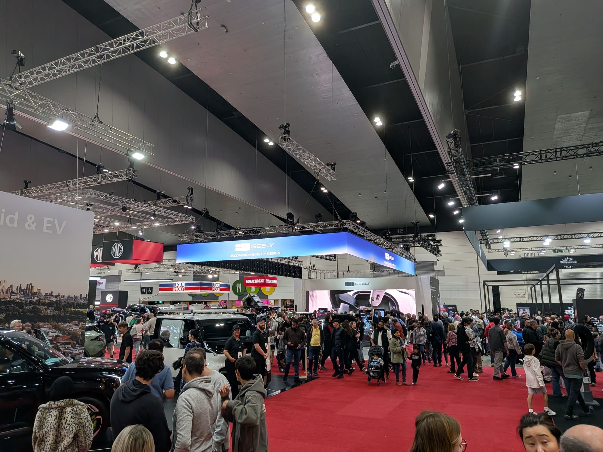 Busy motor show floor with Geely booth in background and visitors walking across red carpet - Encore Event Technologies