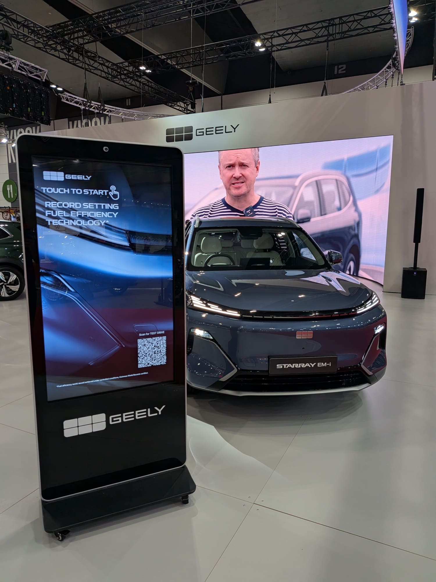 Geely SUV front display with interactive touchscreen kiosk and large LED video wall at motor show stand - Encore Event Technologies