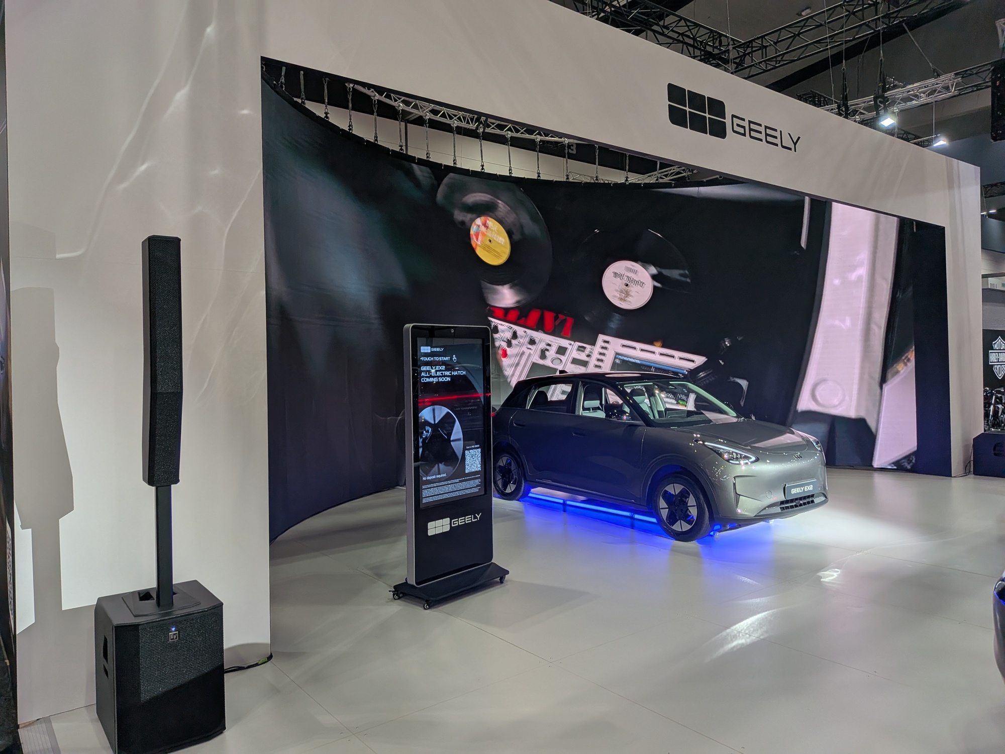 Geely vehicle display with curved LED video wall backdrop and interactive touchscreen kiosk in exhibition booth - Encore Event Technologies