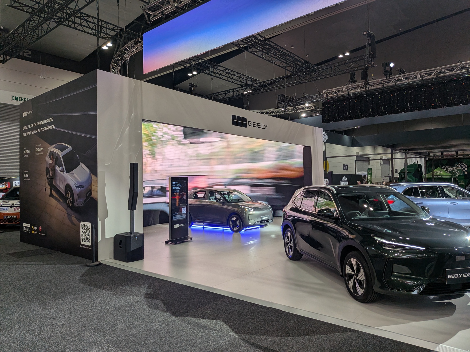 Geely exhibition booth with animated LED screen background, displayed vehicles and lighting rig above stand - Encore Event Technologies