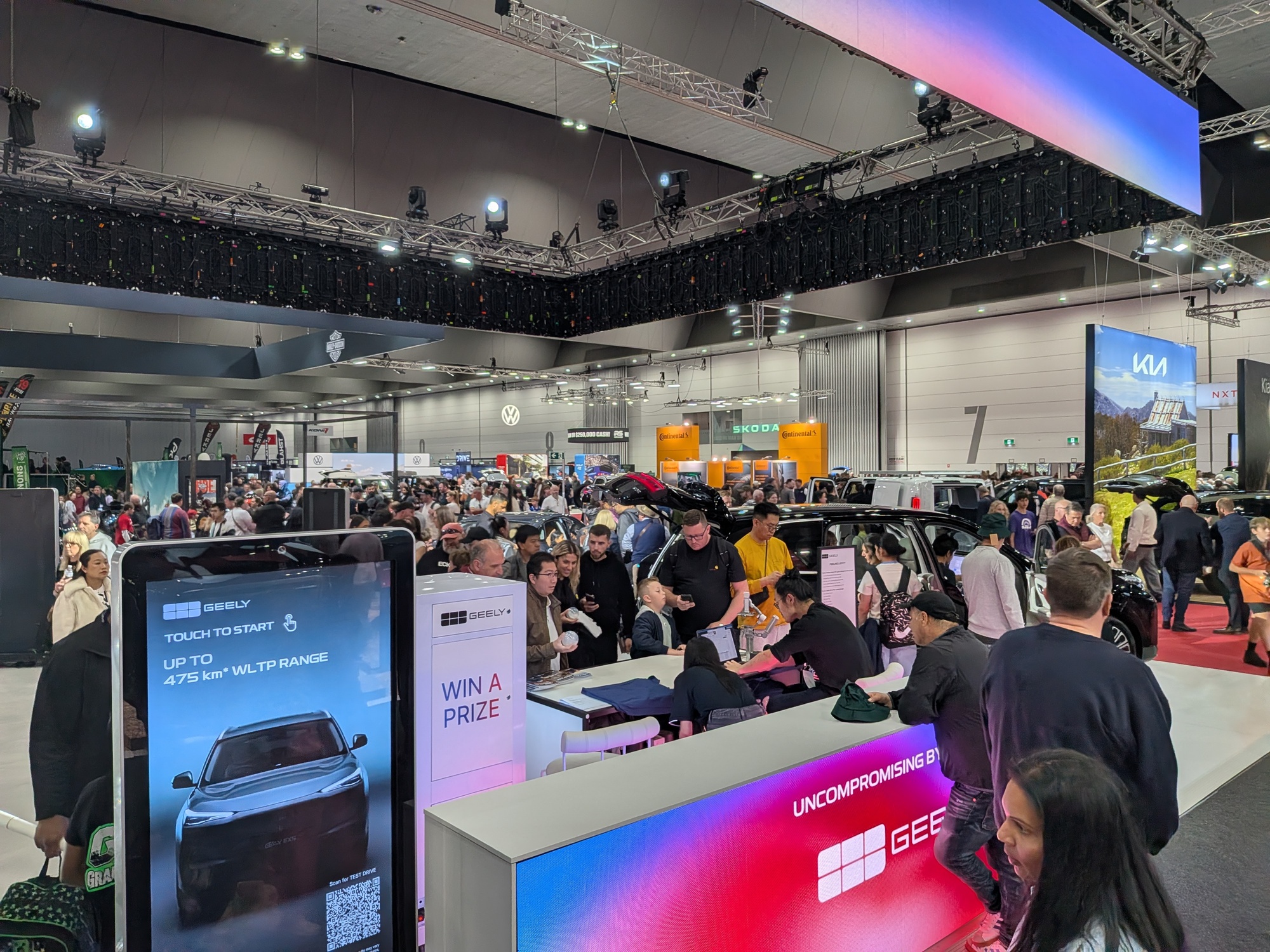 Busy Geely activation counter with “Win a Prize” sign, digital kiosks and large crowd engagement at motor show stand - Encore Event Technologies