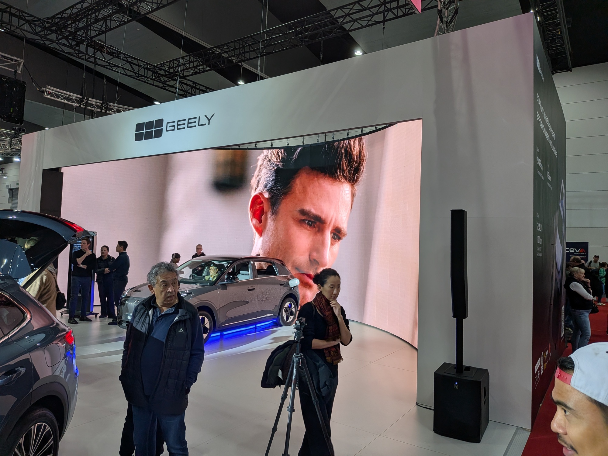 Large curved LED screen at Geely booth displaying presenter video with vehicle positioned in front - Encore Event Technologies