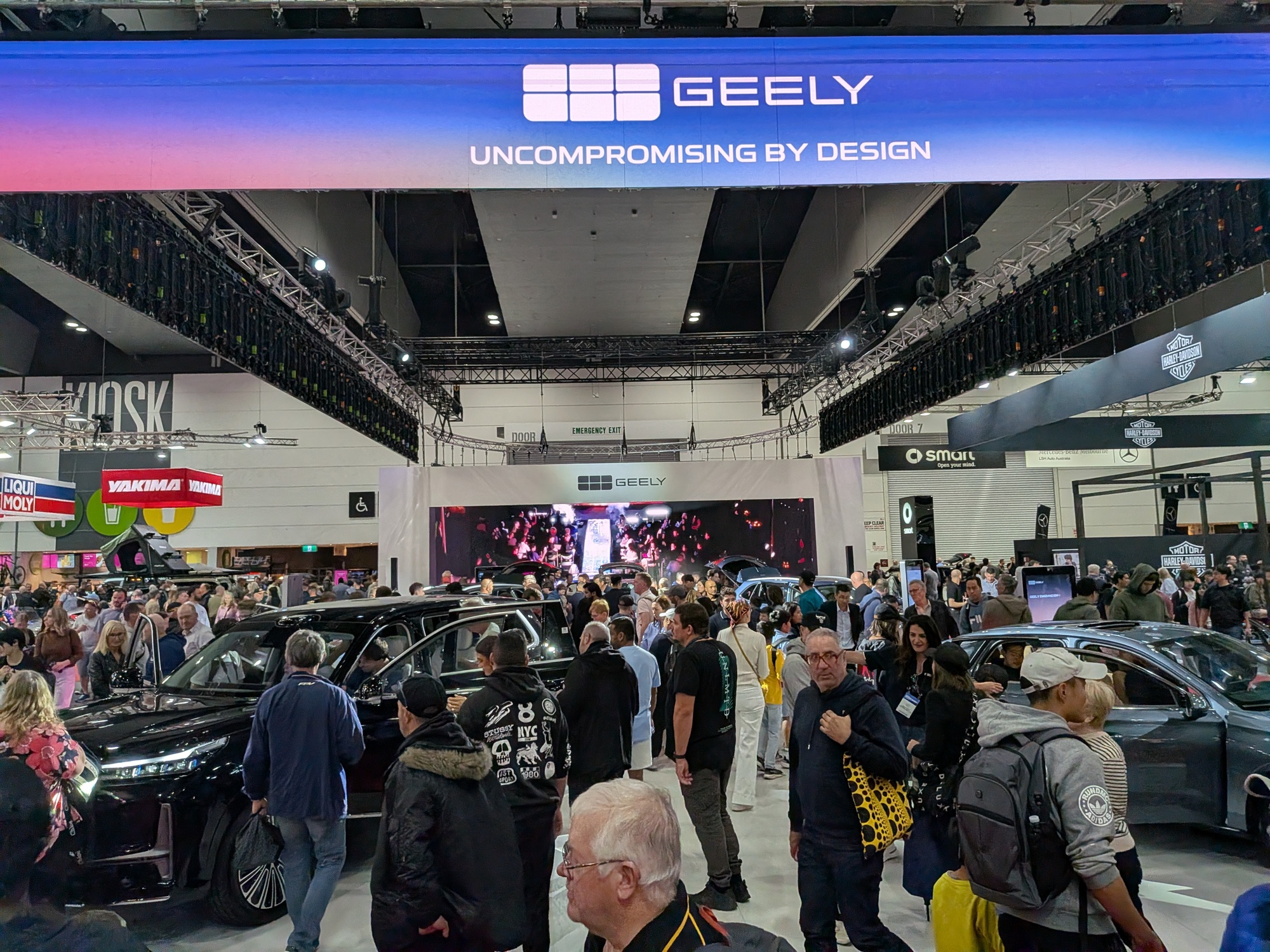 Busy Geely exhibition area with large LED screen backdrop and attendees gathered around featured vehicles - Encore Event Technologies