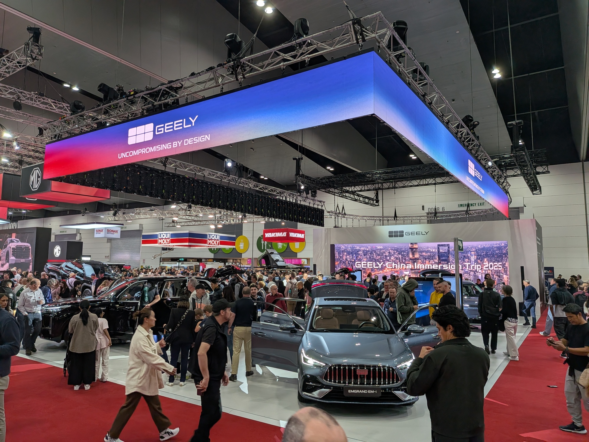 Geely booth with overhead branding cube, vehicles on display and high visitor engagement across platform - Encore Event Technologies