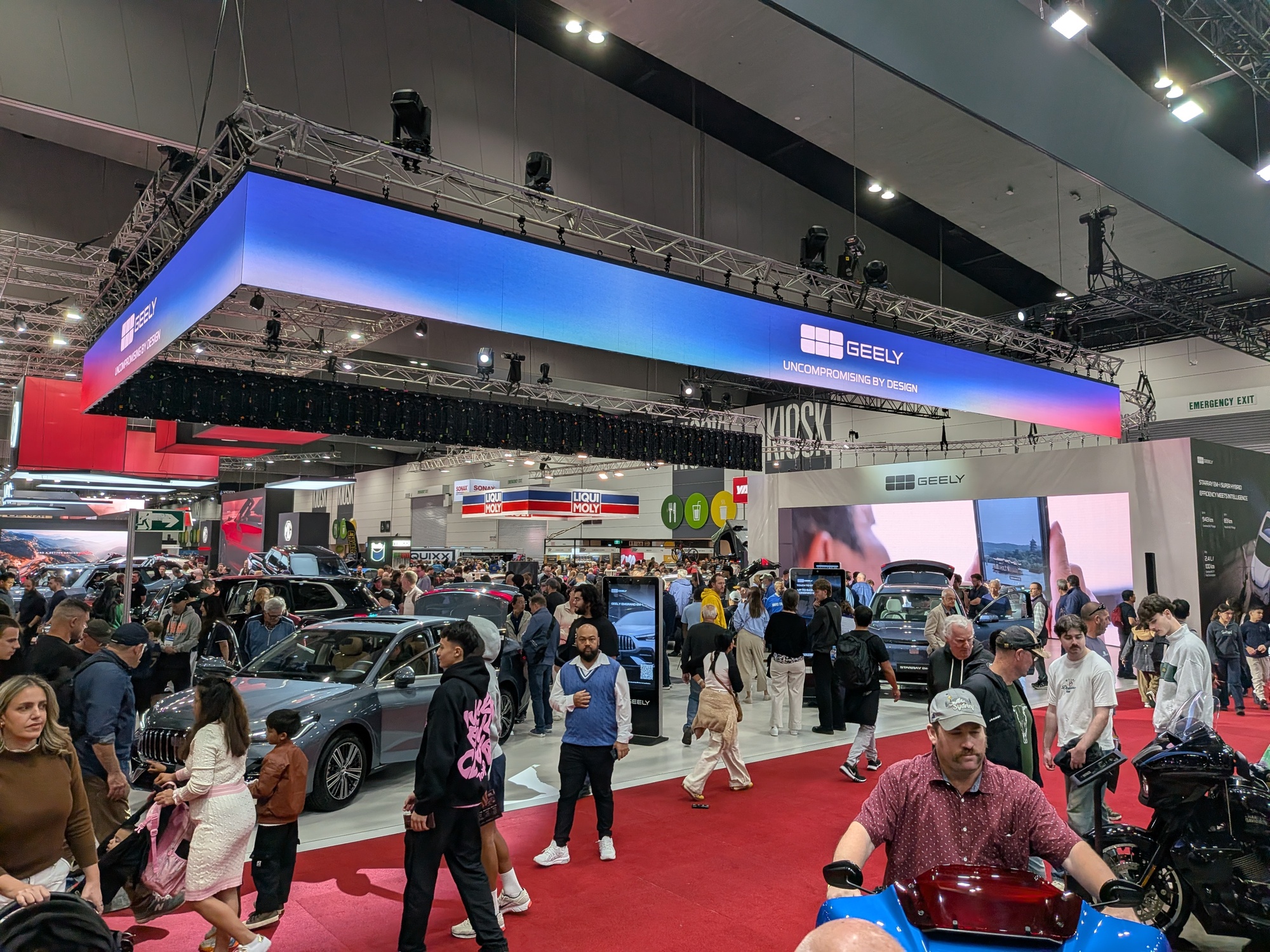 Wide shot of Geely stand featuring overhead illuminated banner, LED wall and heavy foot traffic - Encore Event Technologies