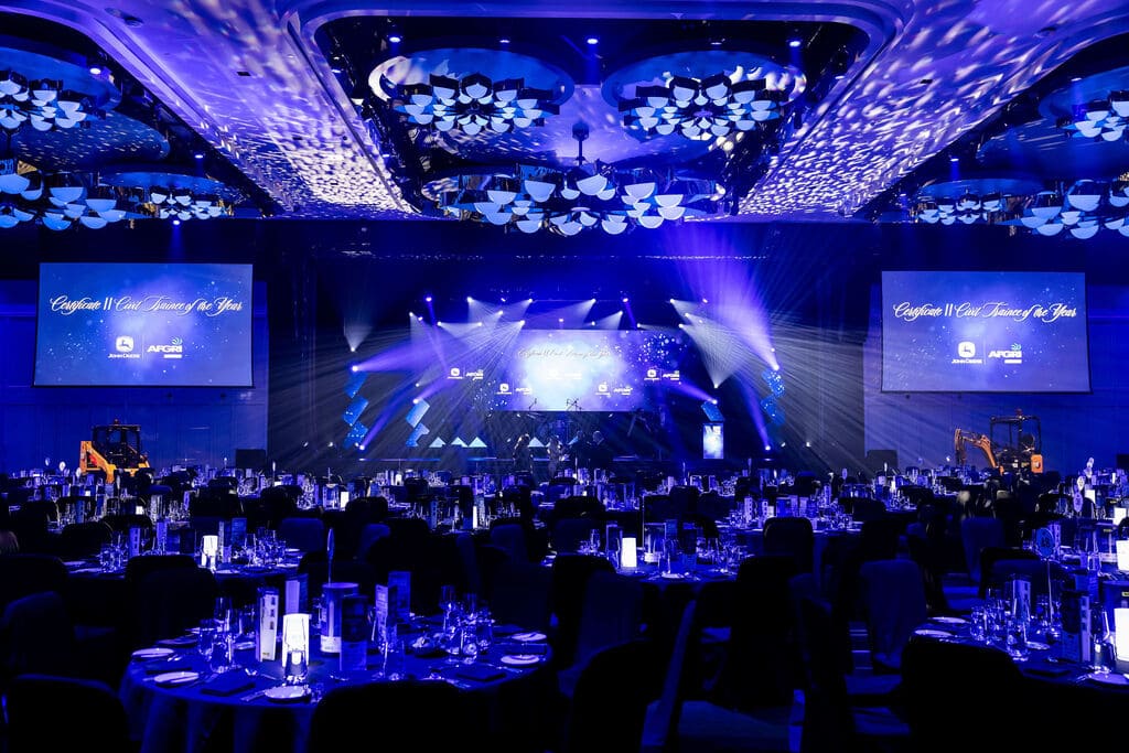 Large gala awards event setup at Crown Perth ballroom with stage lighting, projection screens, and banquet tables prepared for guests – Encore Event Technologies