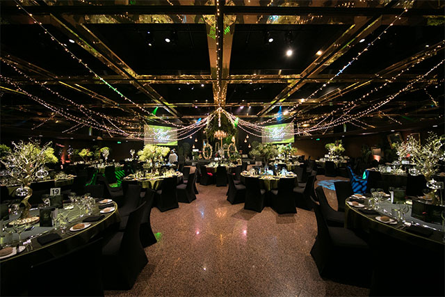 Wide view of an enchanted forest themed event space with fairy lights draped across the ceiling and styled banquet tables – Encore Event Technologies