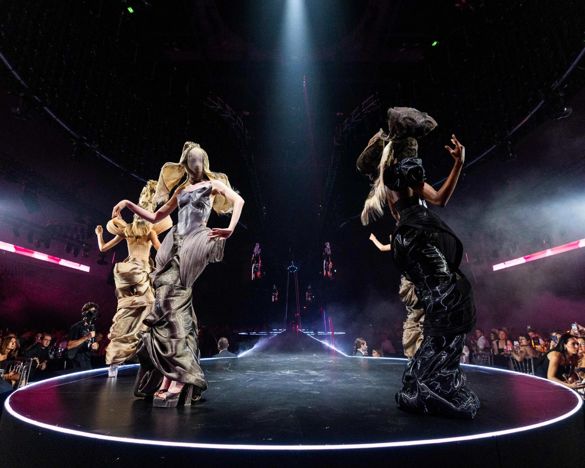Performers on an illuminated runway surrounded by immersive screens and theatrical lighting - Encore Event Technologies
