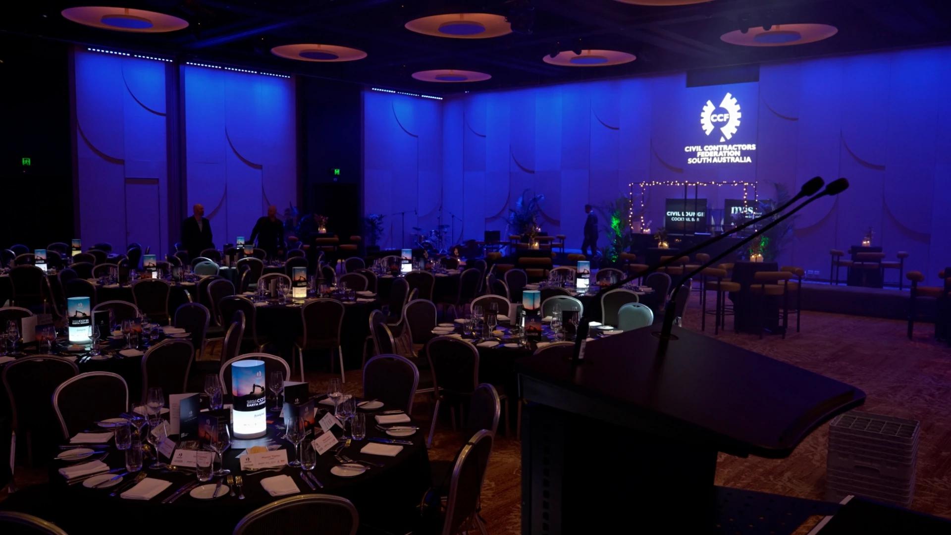 Wide view of the CCF SA Earth Awards ballroom with blue lighting, dining tables and projected CCF branding - Encore APAC