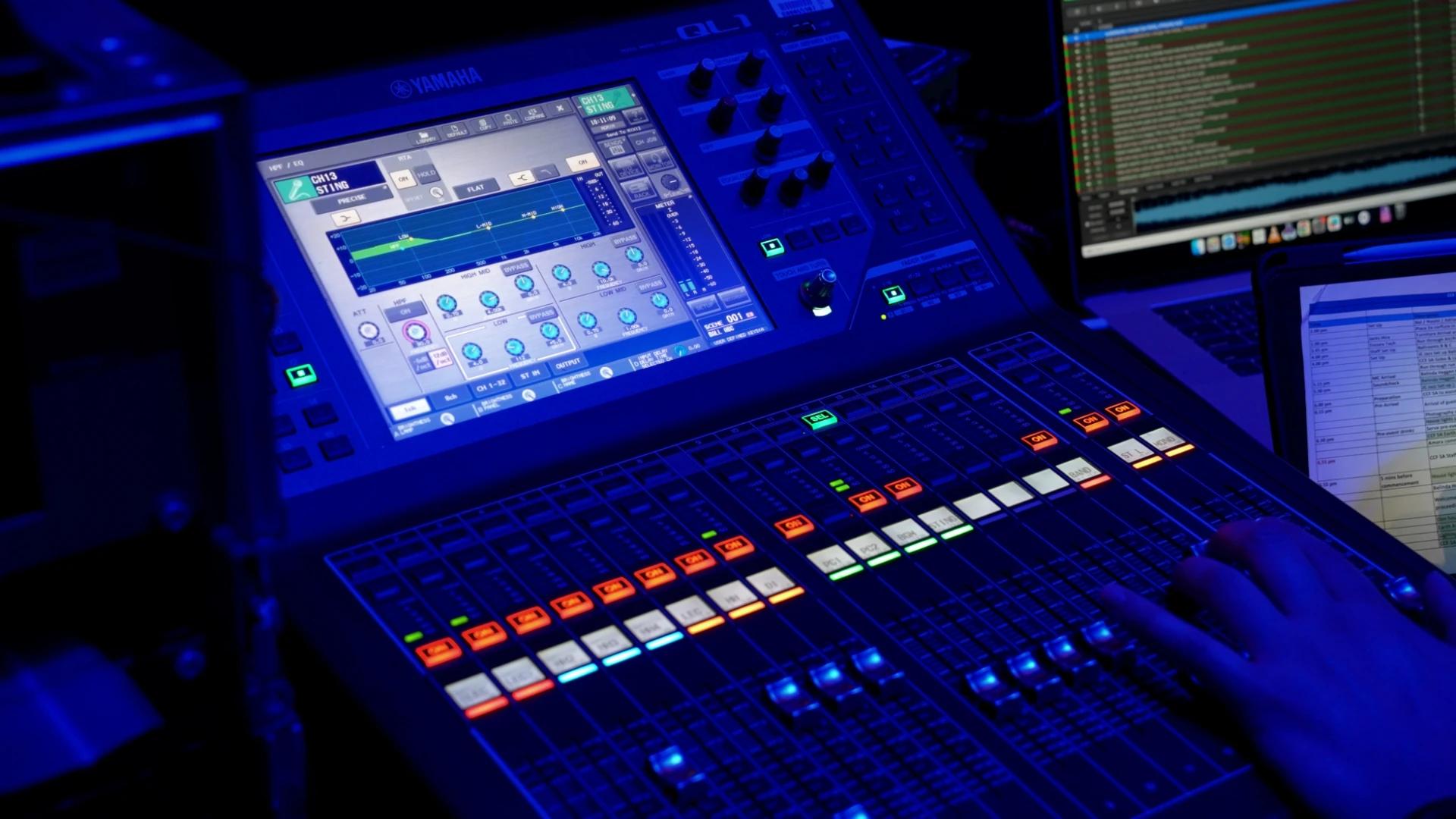 Yamaha digital audio mixing console and production computers under blue event lighting - Encore APAC