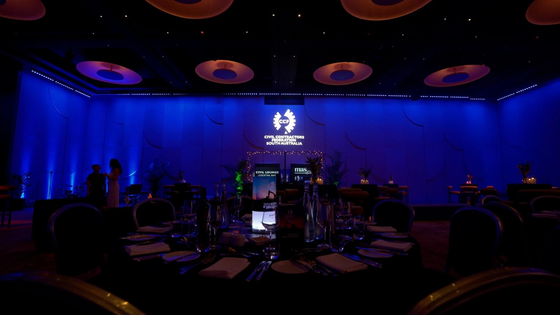 Wide view of the CCF SA Earth Awards ballroom with blue lighting, dining tables and projected CCF branding - Encore APAC
