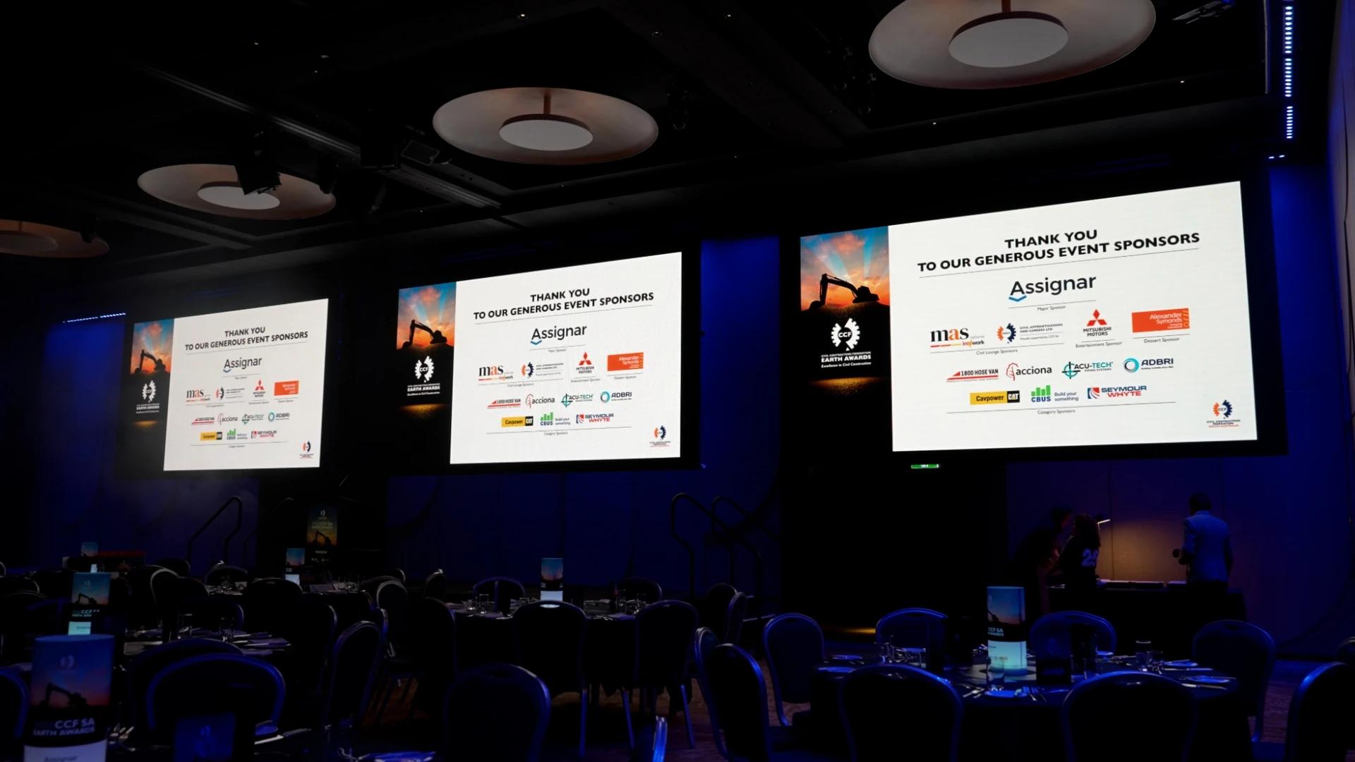 Three large presentation screens displaying sponsor acknowledgements inside the CCF SA Earth Awards venue - Encore APAC