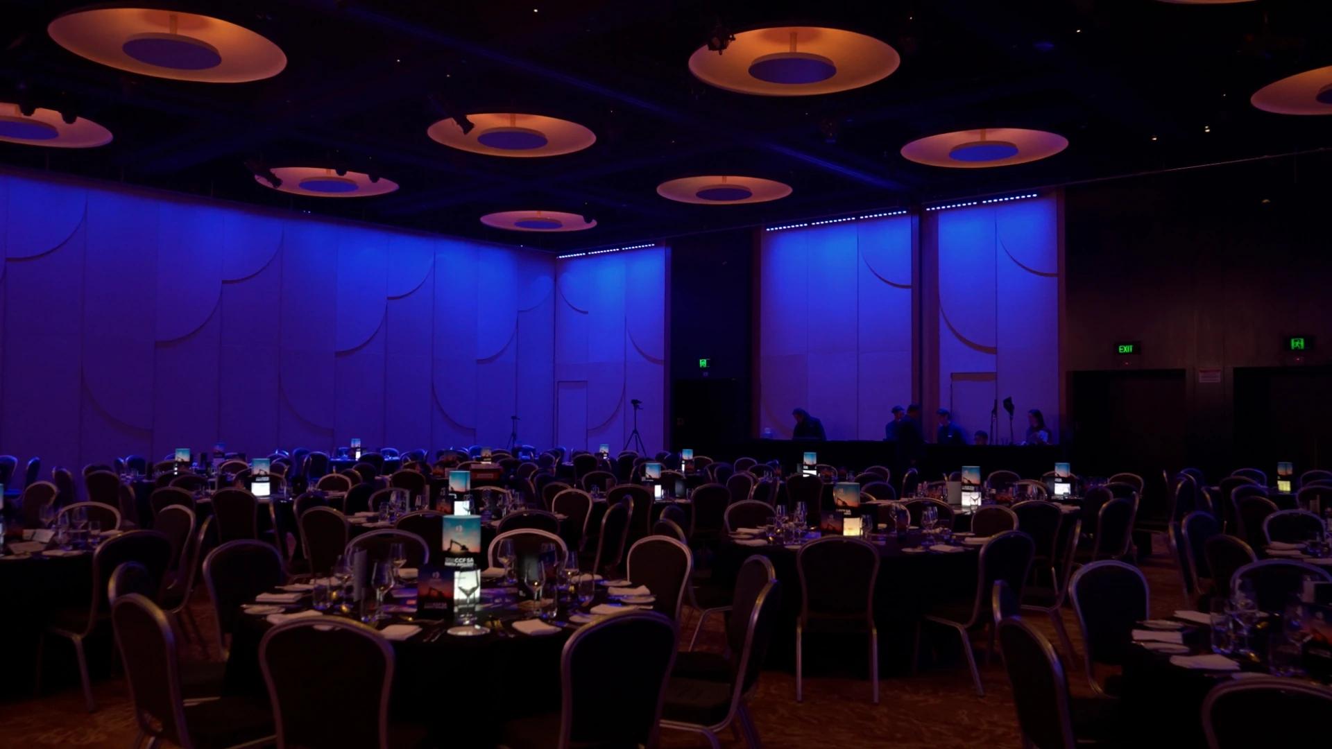Wide view of the CCF SA Earth Awards ballroom with blue lighting, dining tables and projected CCF branding - Encore APAC